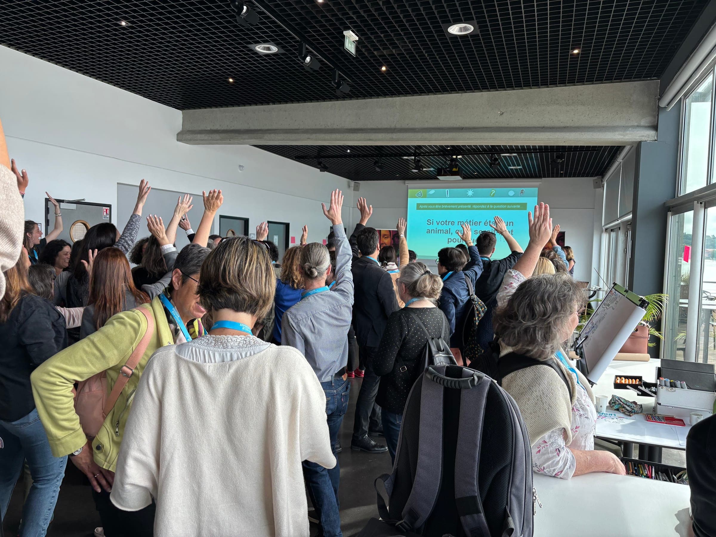 Une salle de participants lève la main pour faire le silence